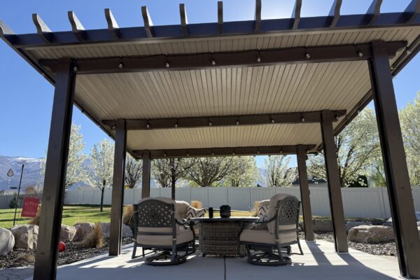 Outdoor dining area under a pergola-style patio cover with seating and table setup
