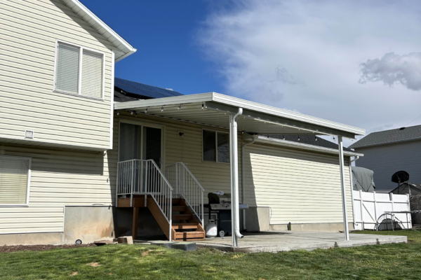 Attached aluminum patio cover extending from a home, creating a covered outdoor seating area