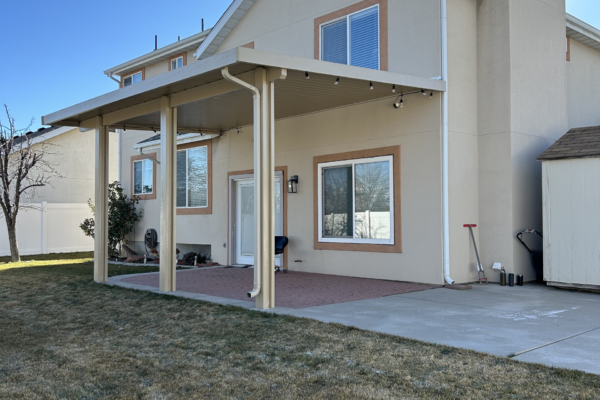 Backyard patio with extended roof cover supported by posts, offering protection and outdoor usability