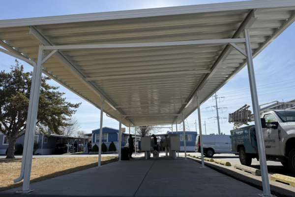 Large metal awning structure designed to cover RVs or vehicles, providing full overhead protection