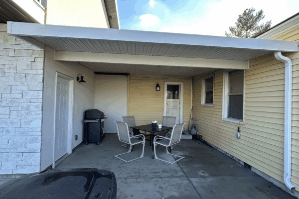 Backyard patio with outdoor furniture under a metal patio cover for shaded seating