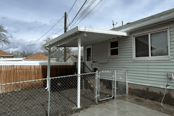 Patio cover installed in a fenced backyard with concrete flooring and clean layout