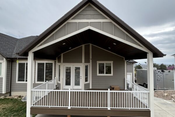 Covered front porch deck with white railing and gable roof design on a modern Utah home