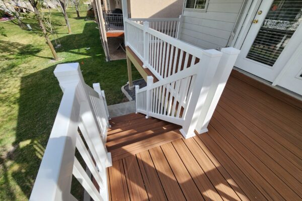 Wooden deck stairs with white railing and clean construction detail leading to a backyard