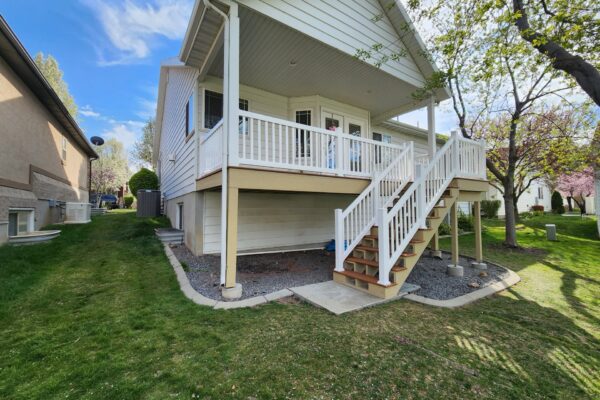 Raised backyard deck with white railing and open space underneath for storage or patio use