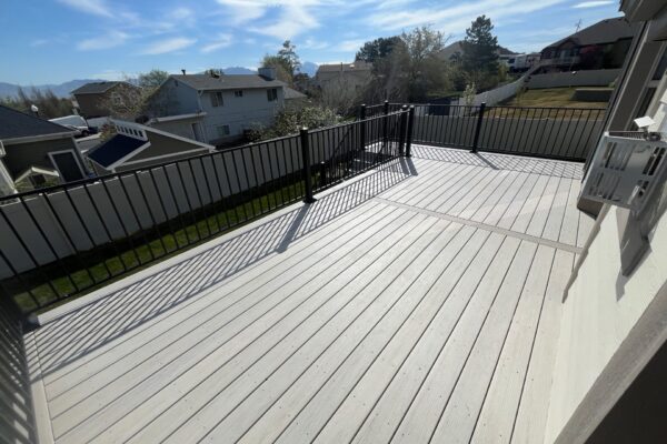 Spacious composite deck with black metal railing overlooking a fenced backyard