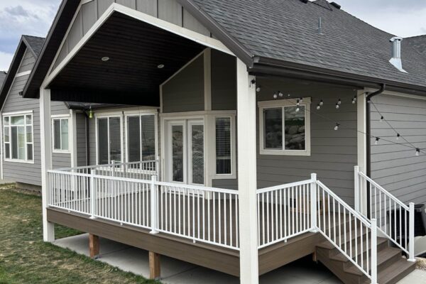 Elevated backyard deck with white railing and stairs leading to ground level on a residential home